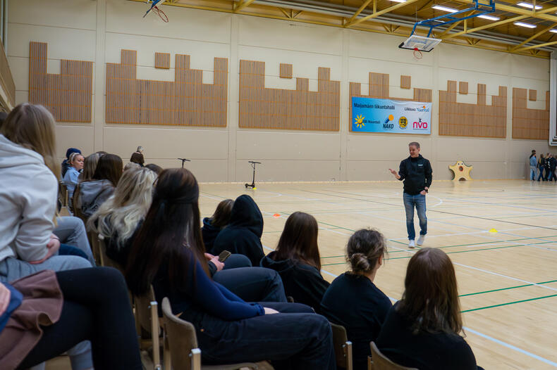 Sami Kivilä puhumassa Maijamäen liikuntahallissa yleisössä istuville nuorille.