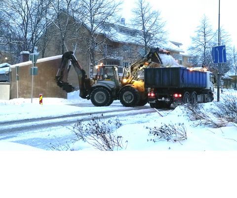 Traktori lastaa lunta kuorma-auton lavalle