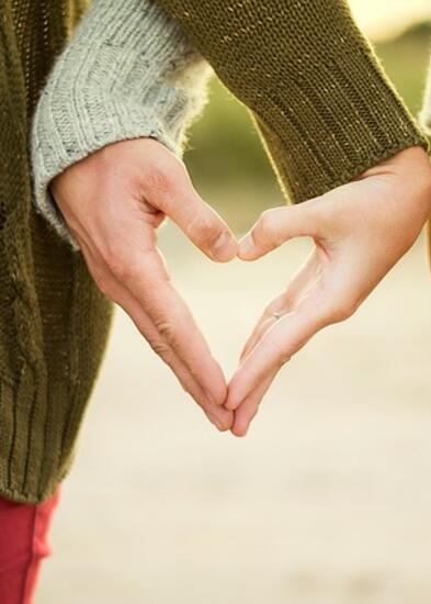 Kaksi ihmistä pitävät toisiaan kädestä, niin että kädet muodostavat sydänkuvion