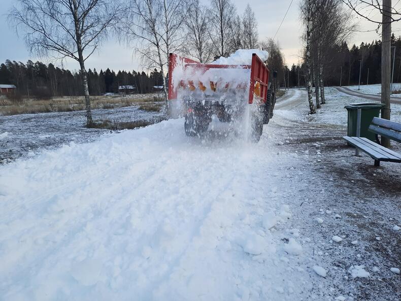 Kuorma-auto ajaa ja lavalta valuu lunta maahan ladun paikalle.