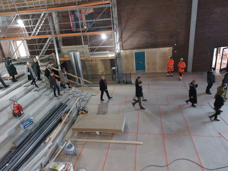 Ihmisiä kävelemässä perhetalon rakenteilla olevassa aulassa.