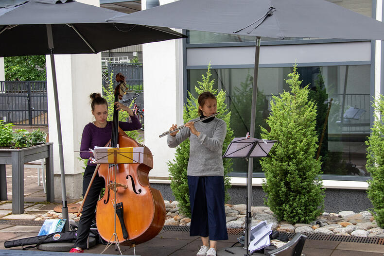 Muusikot soittavat kontrabassoa ja poikkihuilua päivänvarjojen alla.