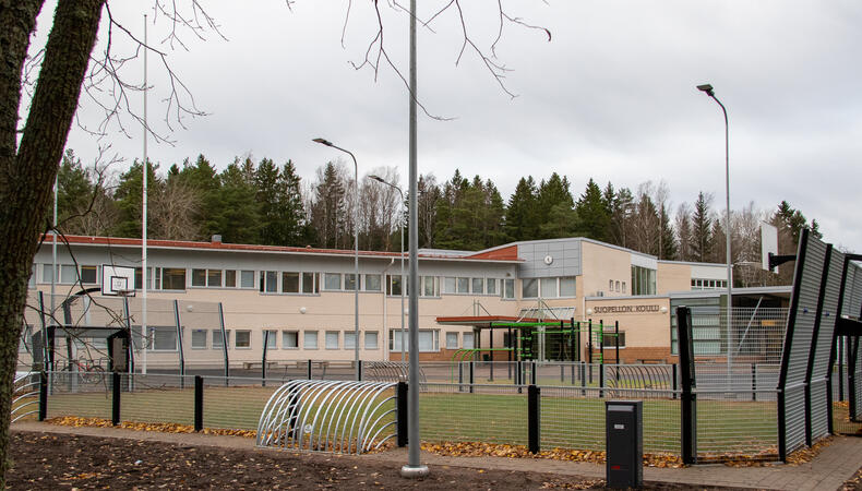 Nurmipäällysteisen peliareenan takana on koulurakennus.