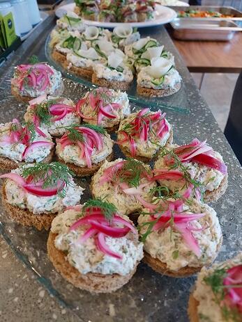 Coktailpaloja tarjottimella, alla ruispohjainen leipä, päällä tahnaa ja päällimmäisenä pikkelöityä punasipulia.