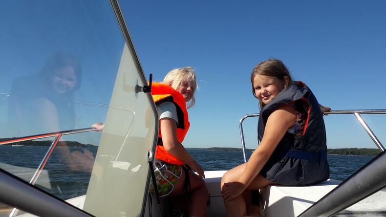Kaksi lasta moottoriveneessä merellä aurinkoisena päivänä.