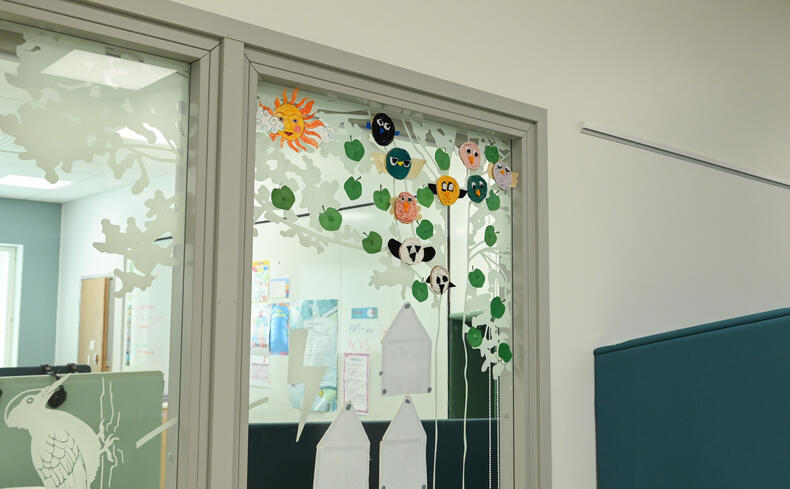 Luokan ikkunassa oppilaiden tekemä haapapuu, jossa on eläimiä ja lehtiä.