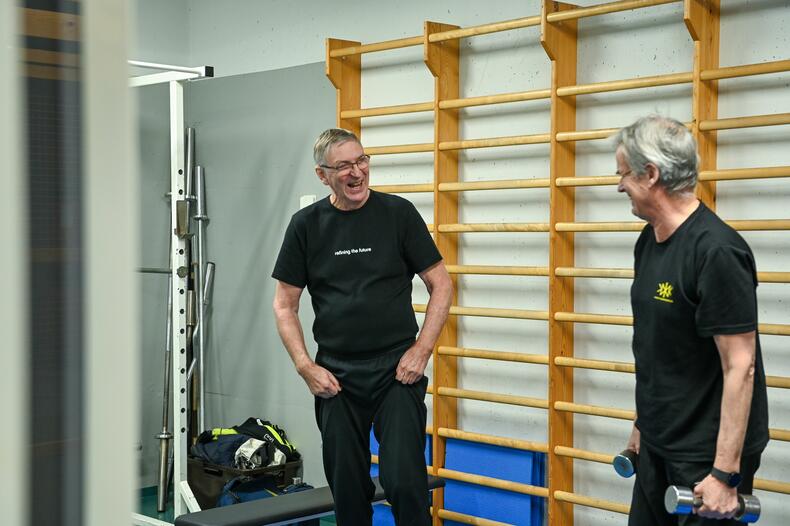 Kaksi miestä naureskelevat kuntosalilla.