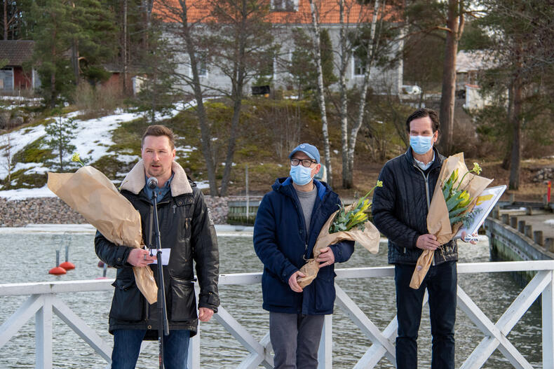 Tuomas Levanto pitää puhetta, Ville Vuorio ja Sami Nurmela seisovat taustalla. Kaikilla on käsissään palkintokukat.