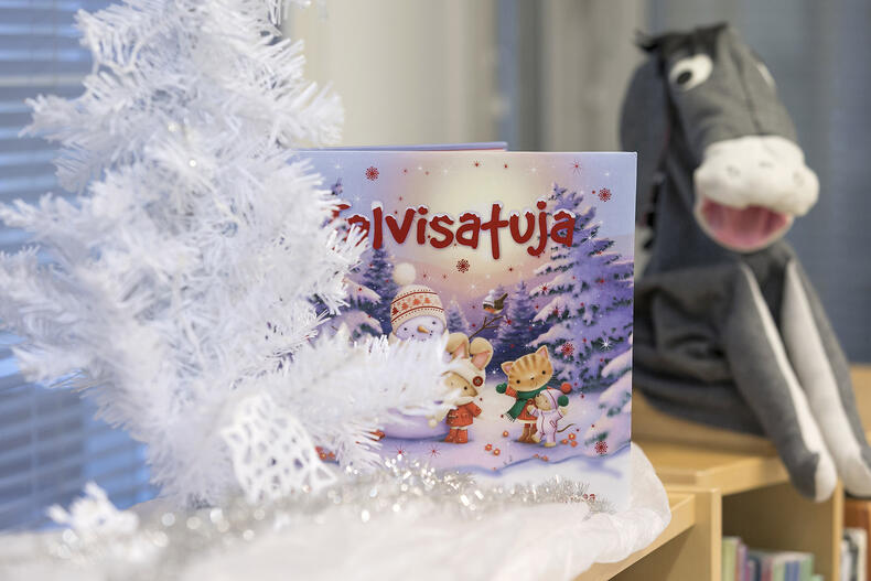 Joulukuusen takaa näkyy kirja sekä Aasi-pehmolelu.