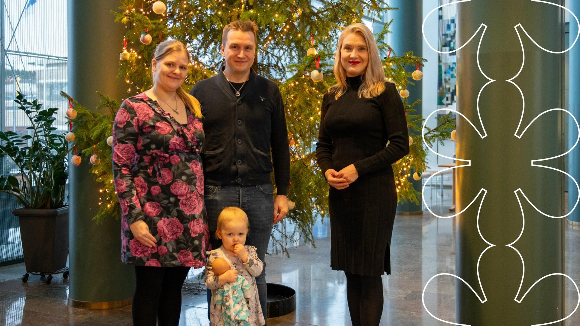 Munterin perhe ja Laura Leppänen hymyilevät kaupungintalon aulan kuusen edessä.