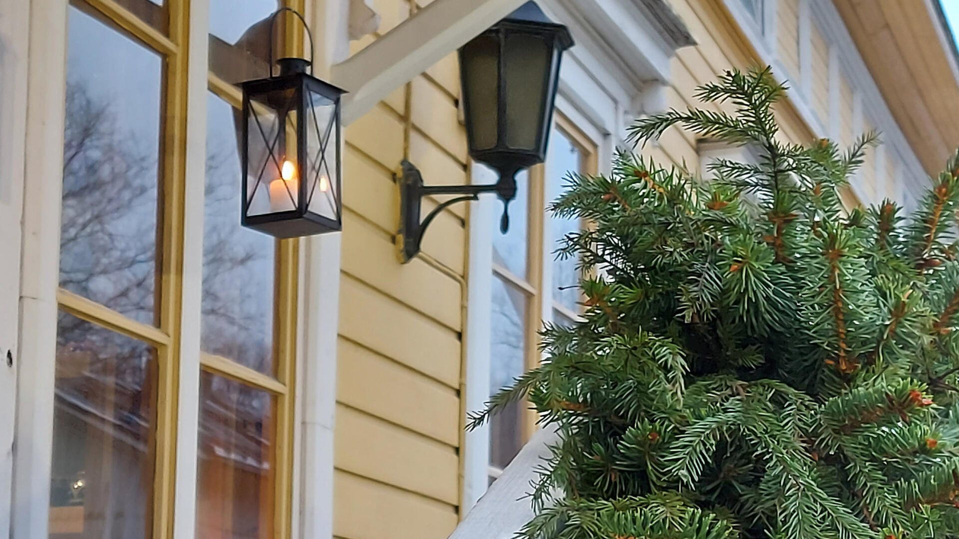 Havuköynnös museon porraskaiteella ja kynttilälyhty roikkuu museon ikkunan edessä.