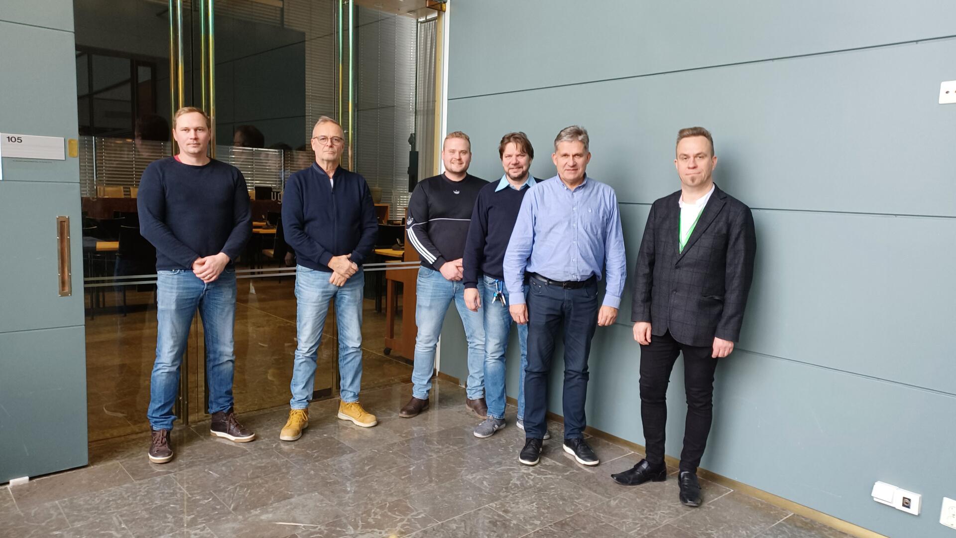 Kaupungintalon käytävällä kuusi miestä rivissä.