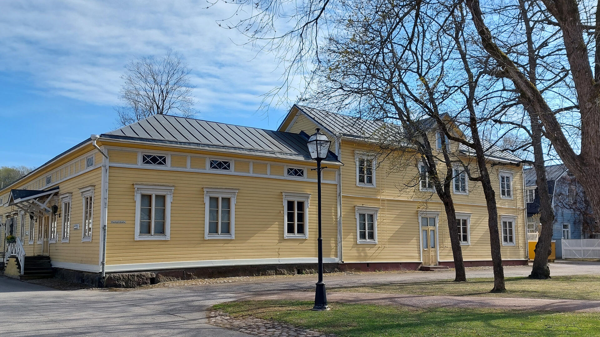 keltaiseksi maalattu puurakennus puiston reunalla