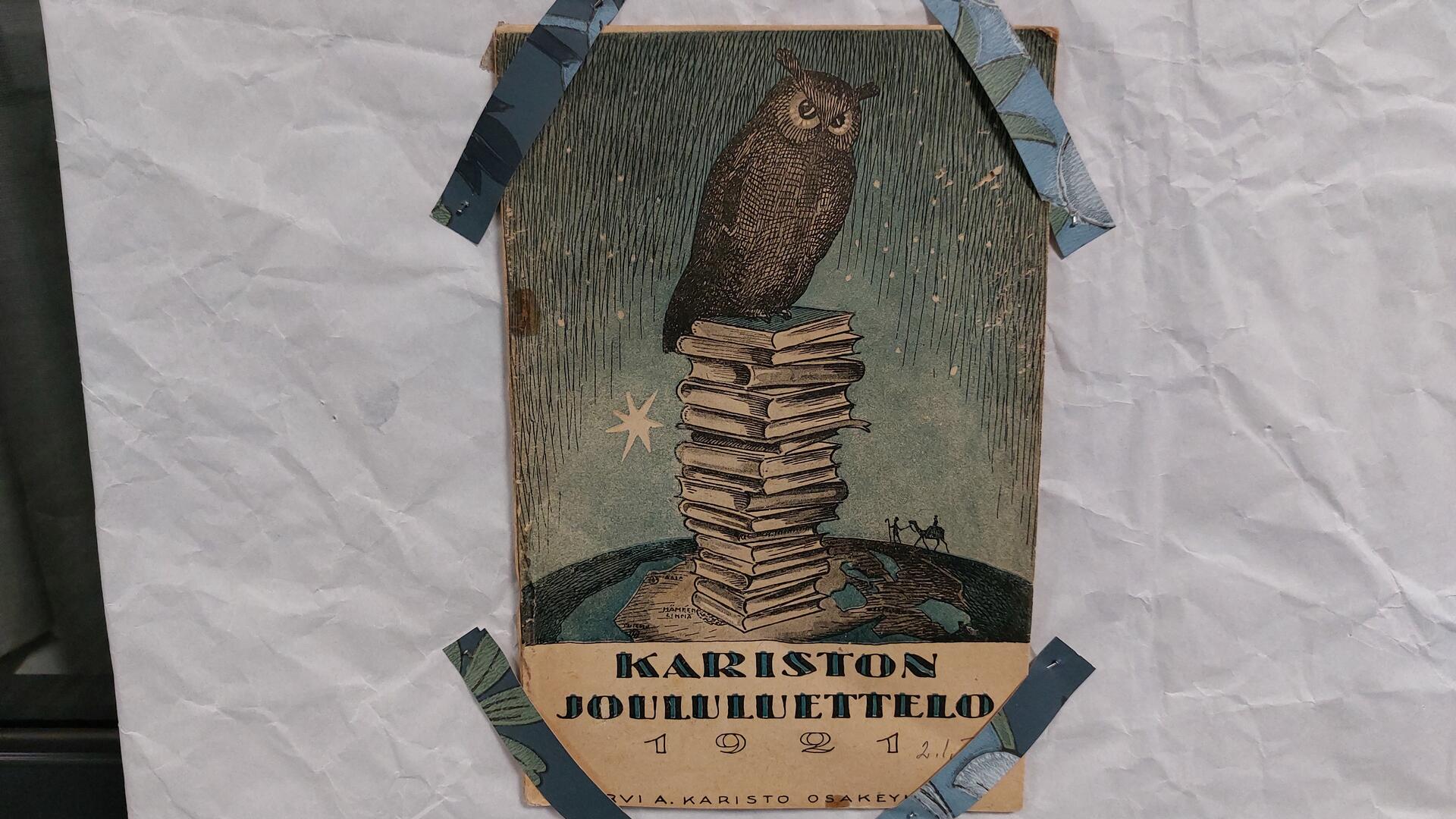 paperitaustalla paperinen luettelo, jonka kannessa pöllö 