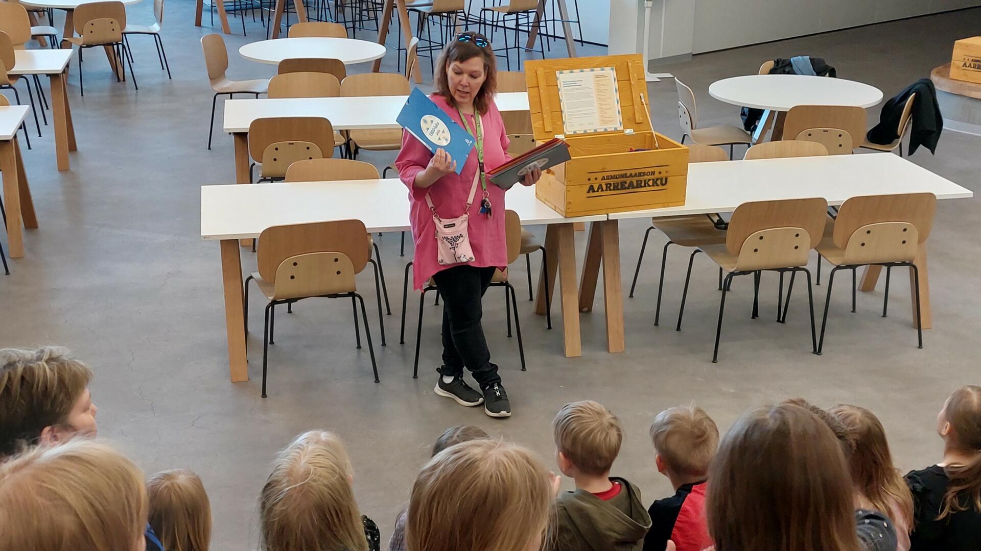 lapsia yleisönä katsomassa naista joka selostaa 