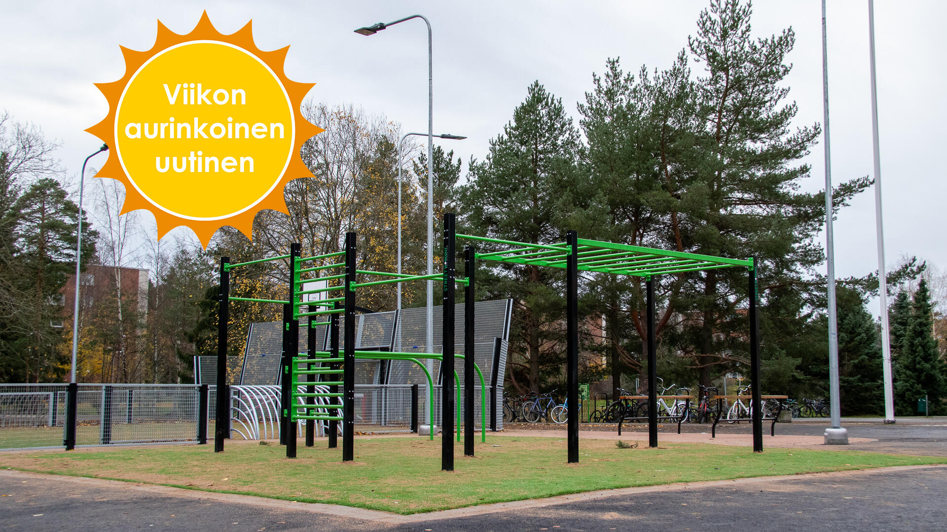 Vihreät street work -välineet asfalttisen pihan keskivaiheilla, takana peliareena. Viikon aurinkoinen uutinen