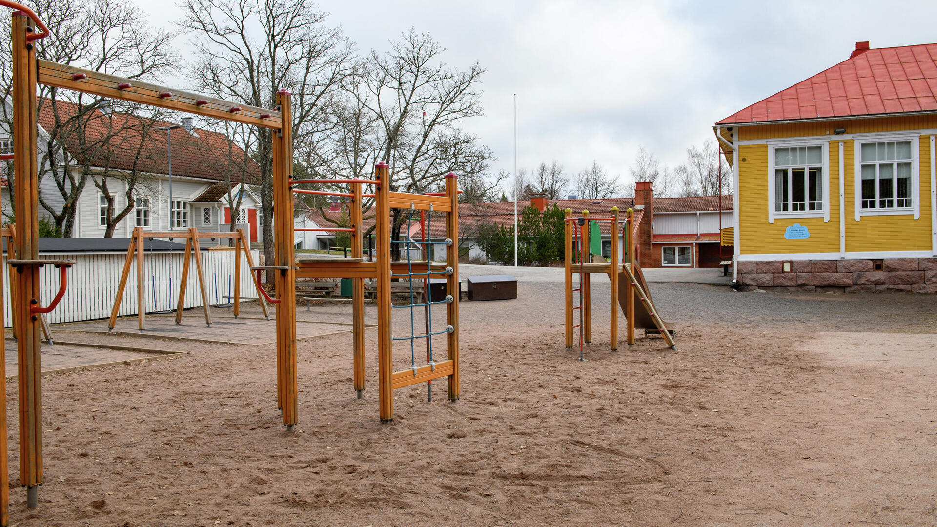 Leikkikentän päässä näkyy Lietsalan koulun keltainen, sininen ja punatiilinen rakennus.