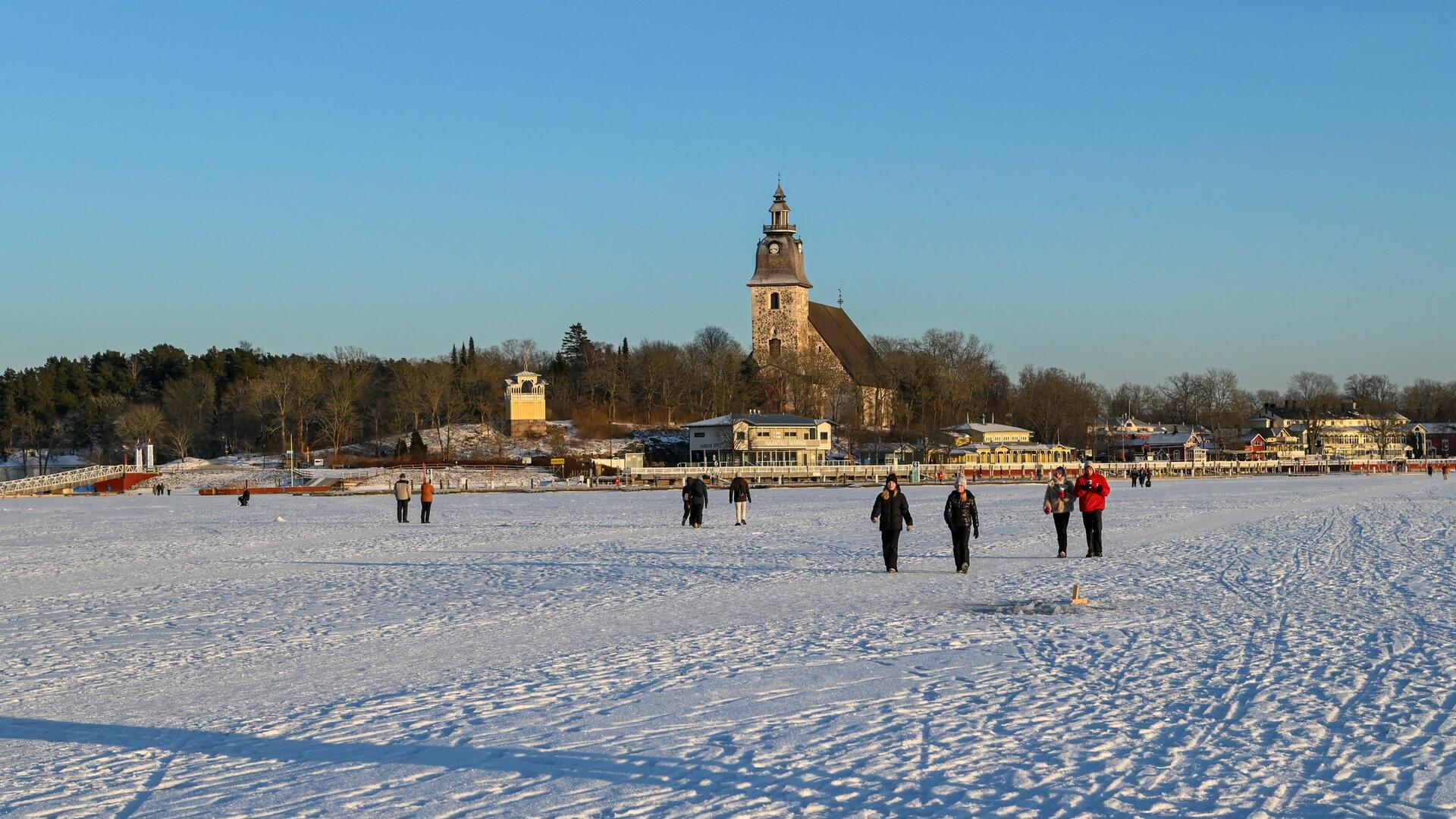 Kävelijöitä talvella merenjäällä Naantalin Vanhankaupungin edustalla.