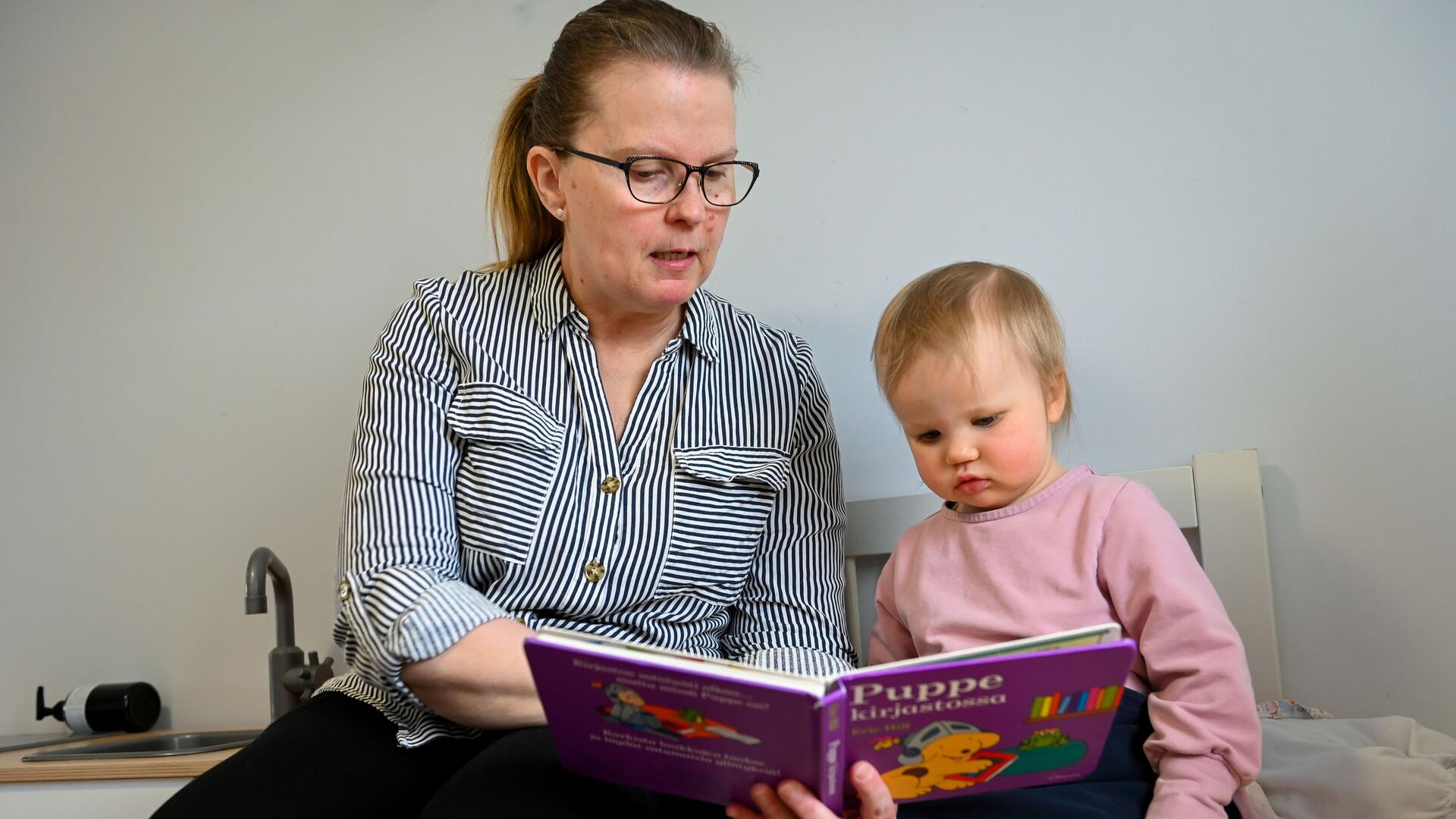 Perhepäivähoitaja lukee satua pienelle lapselle.
