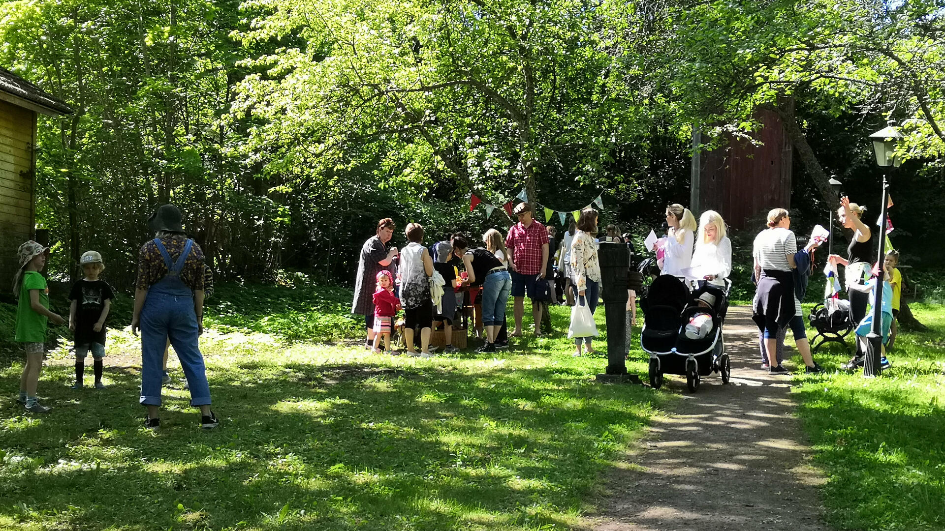 ihmisiä vehreässä puutarhassa kesäisenä päivänä