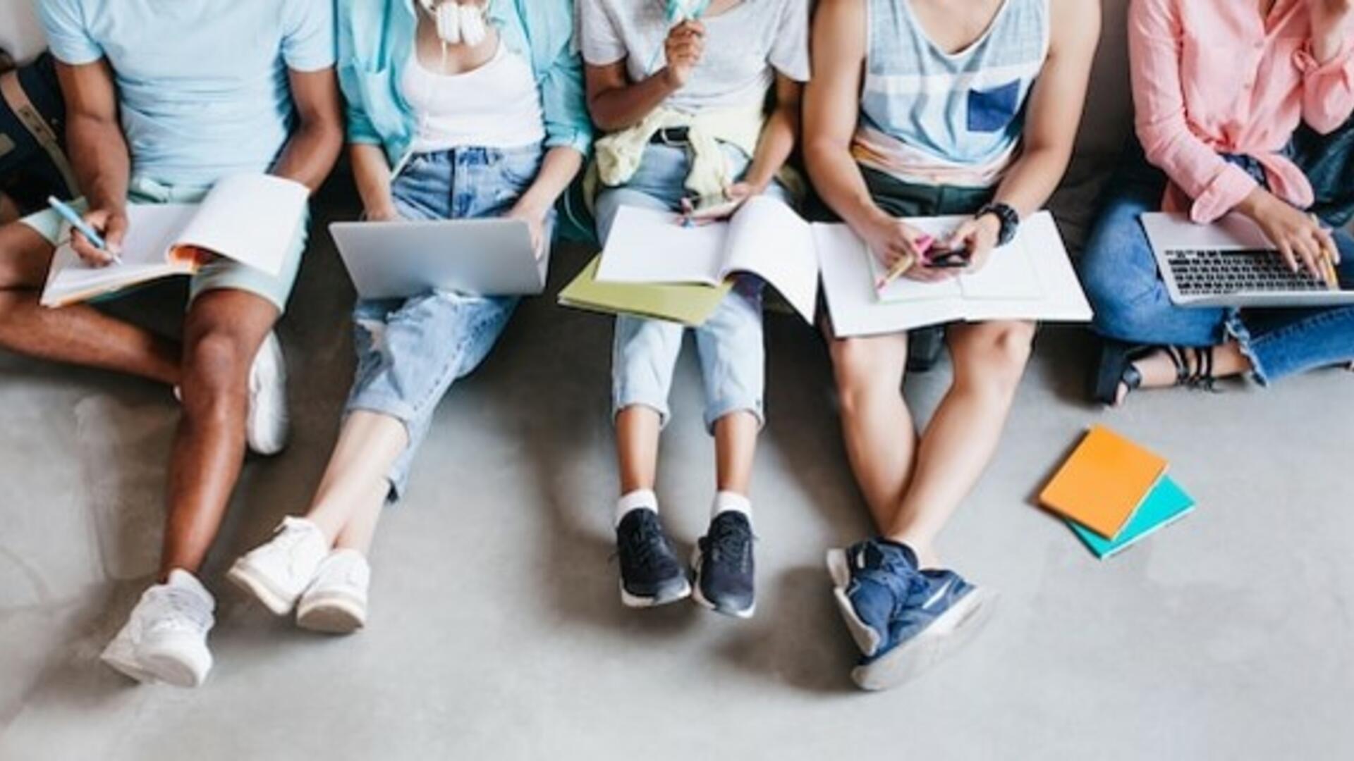 nuoret istuvat lattialla vain jalat näkyvät kuvassa