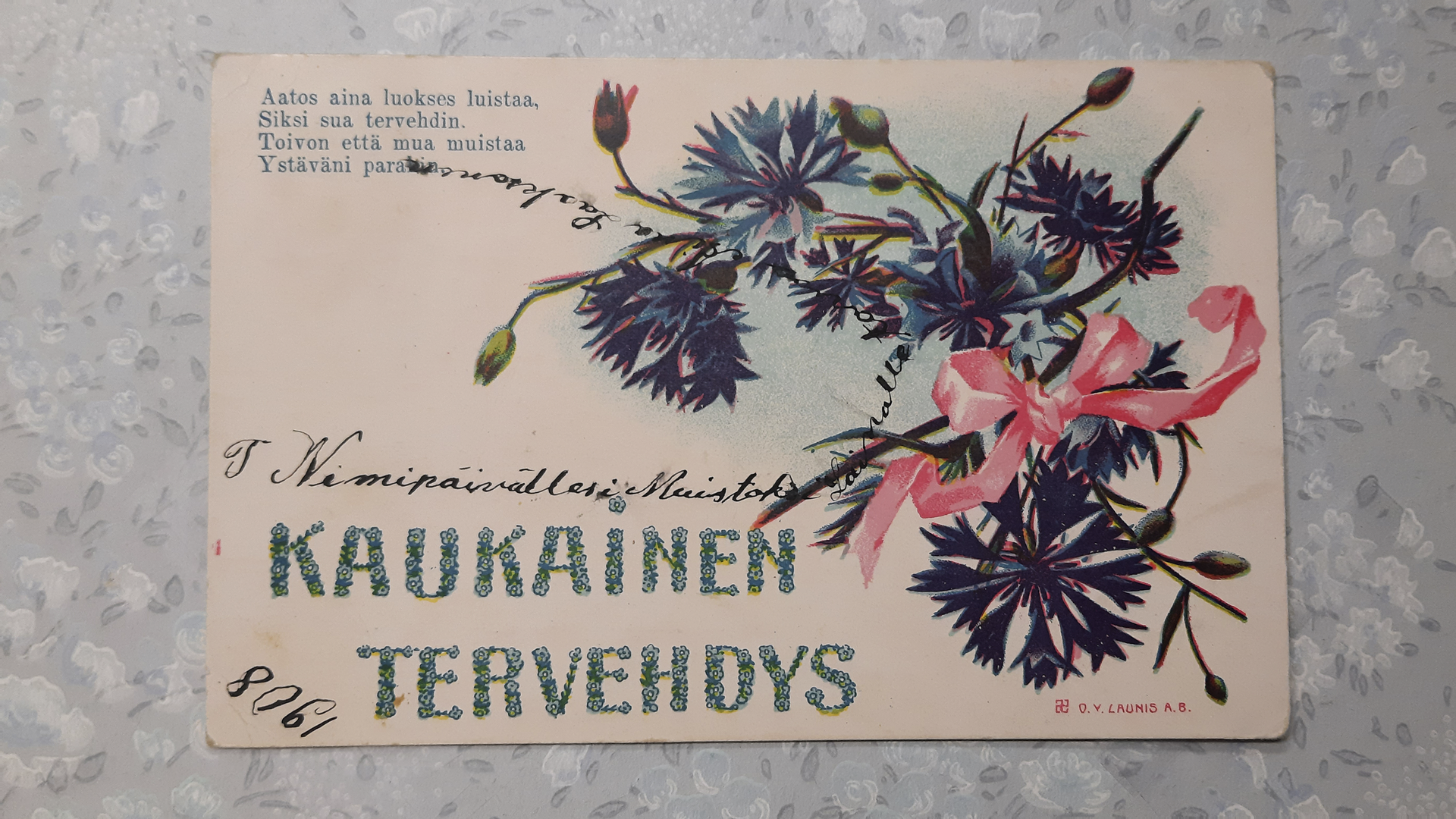 vanha onnittelukortti, jossa painettu runo, onnittelutervehdys ja kukkakuva, sekä käsin kirjoitettu onnitteluteksti