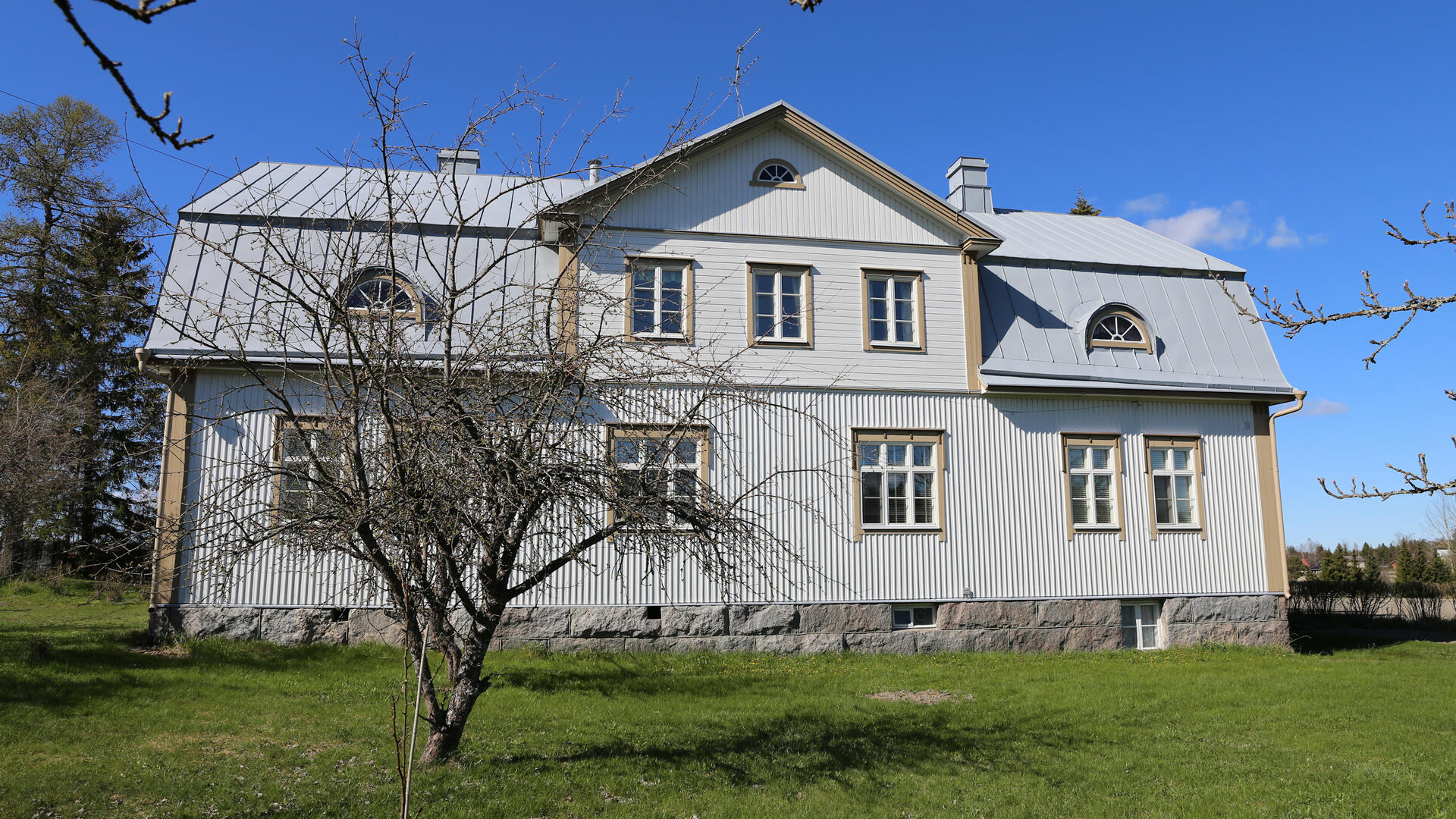 vaaleaksi maalattu puurakennus maisemassa