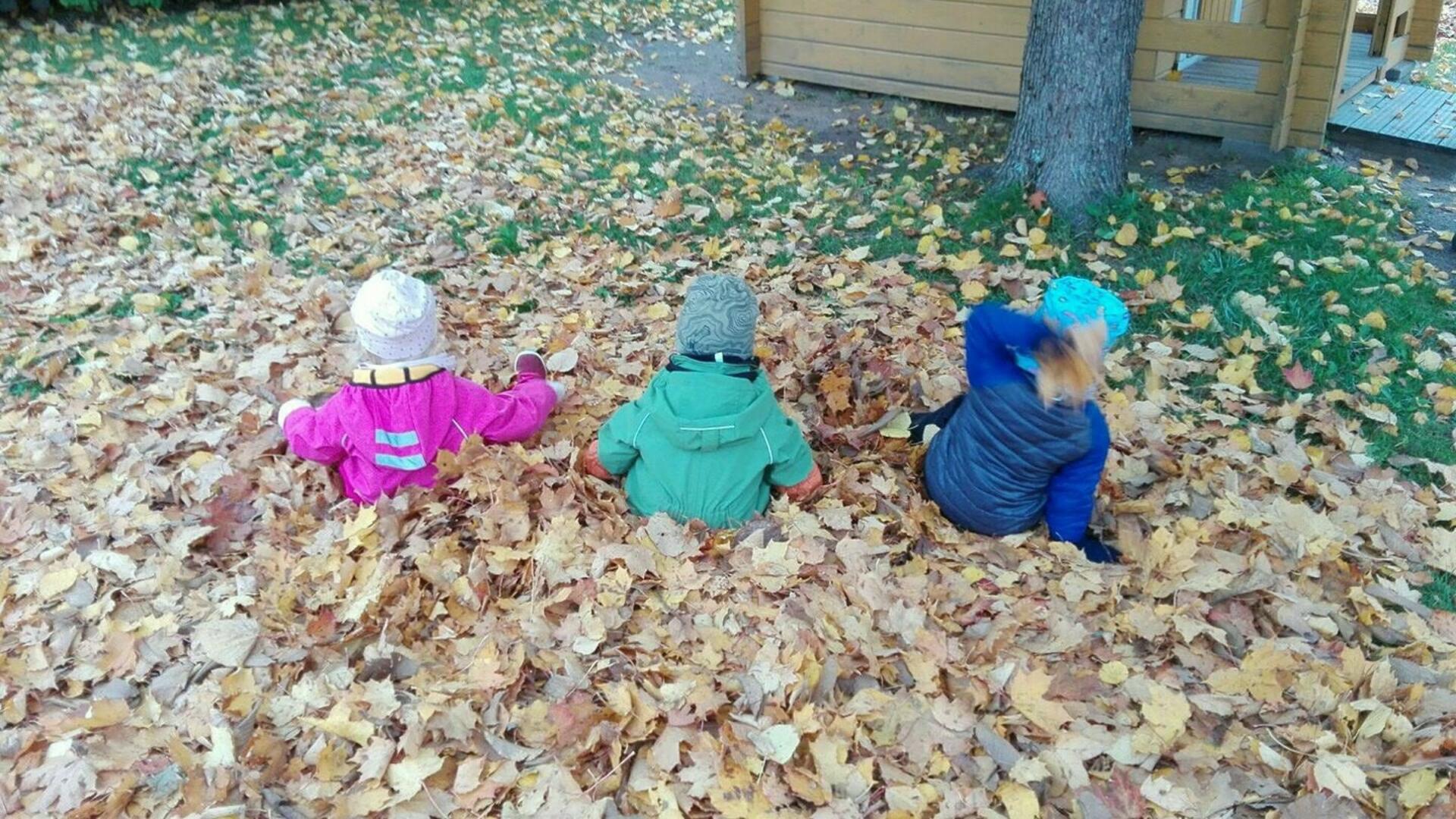 Lapset istumassa lehtikasassa