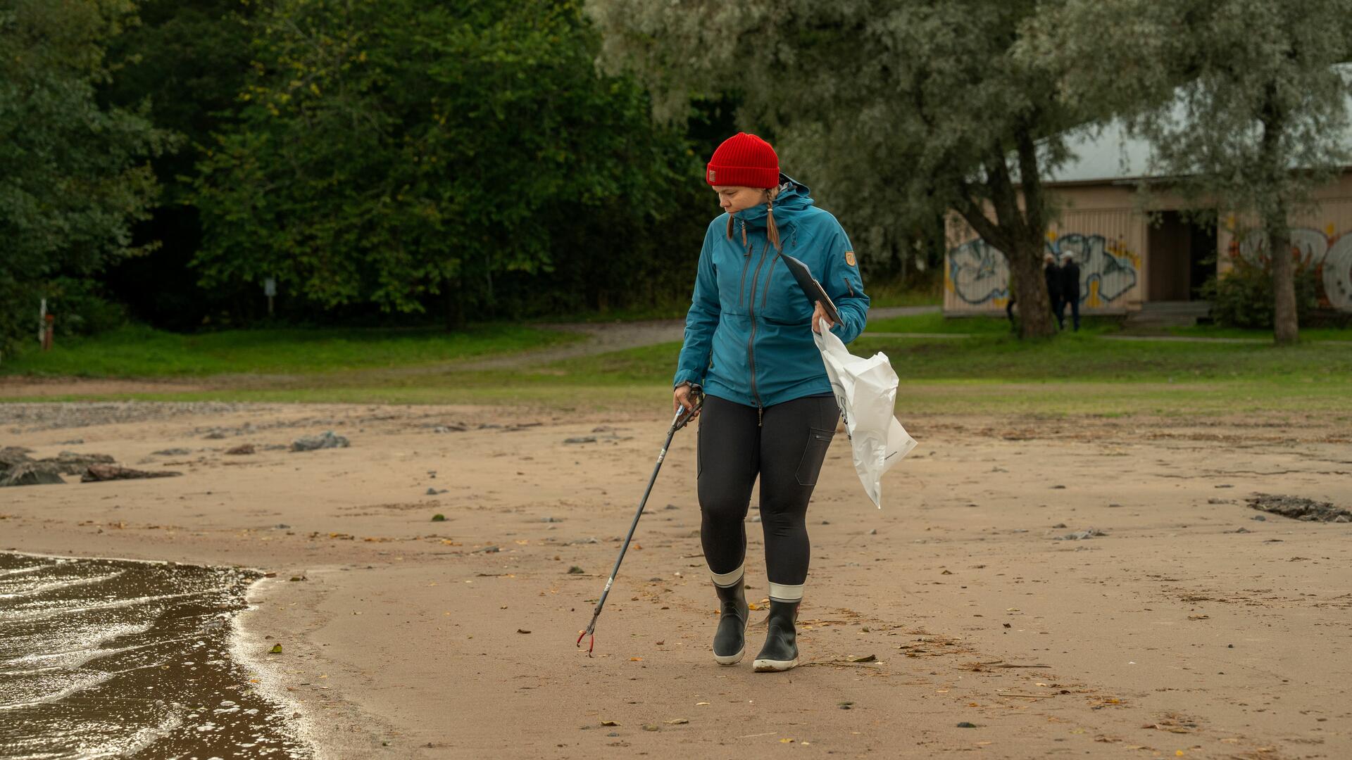 Henkilö kerää roskia rannalla.