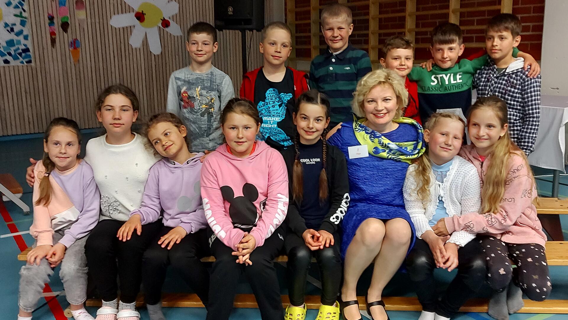 Ryhmäkuva ukrainalaisista oppilaista ja suurlähettiläs Olga Dibrovasta Karvetin koulun liikuntasalissa.