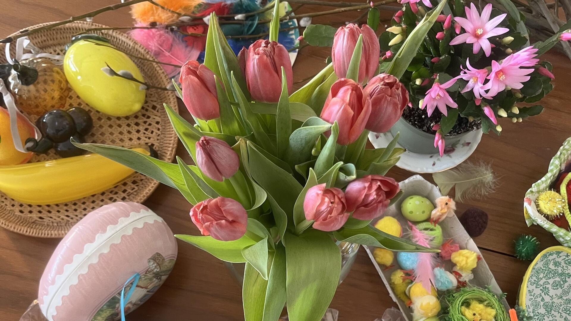 Tulppaaneja ja pääsiäiskoristeita pöydällä.