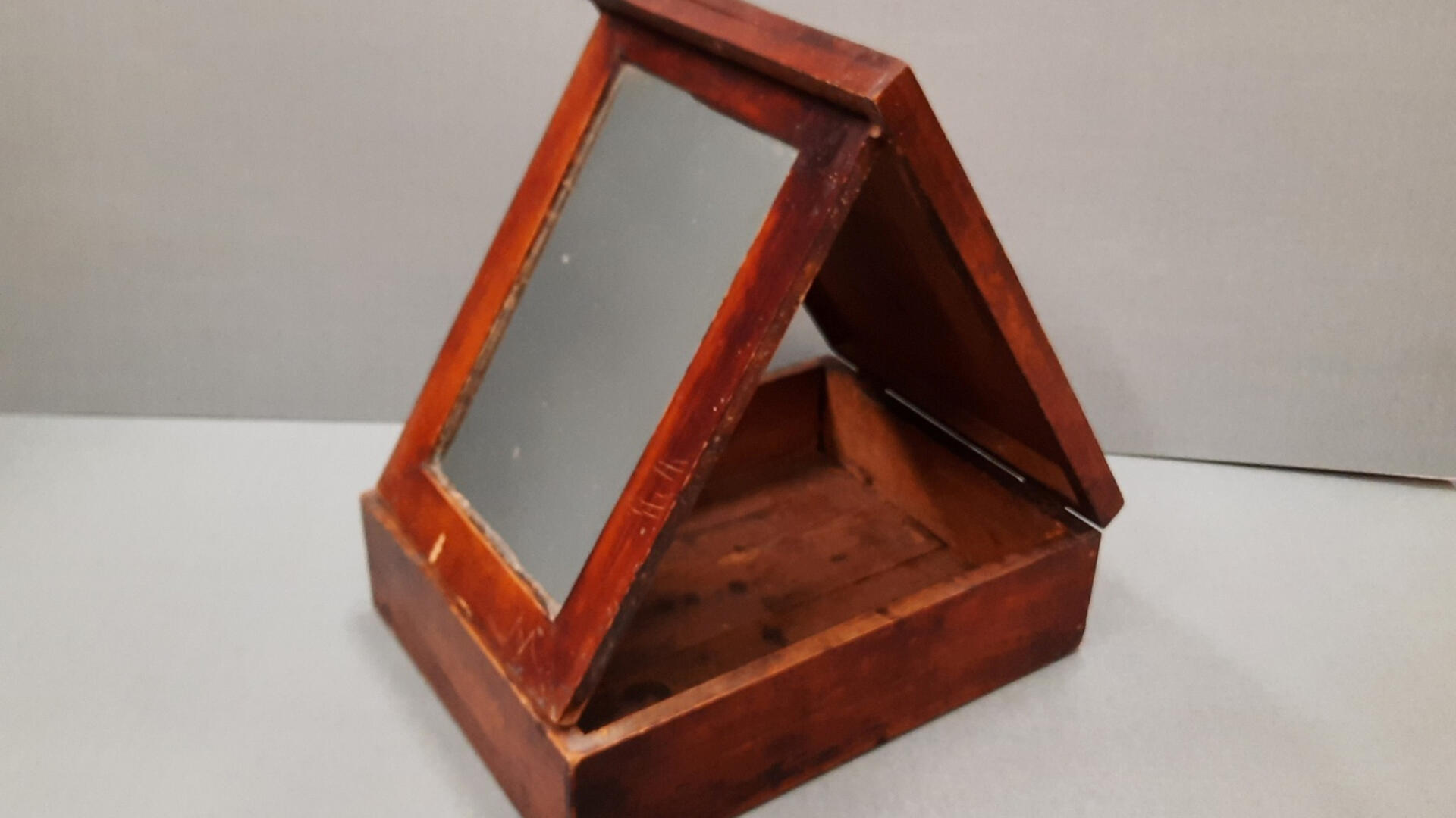 puukehysteinen peili, joka on kiinnitetty laatikkoon ja nojaa puutukeen