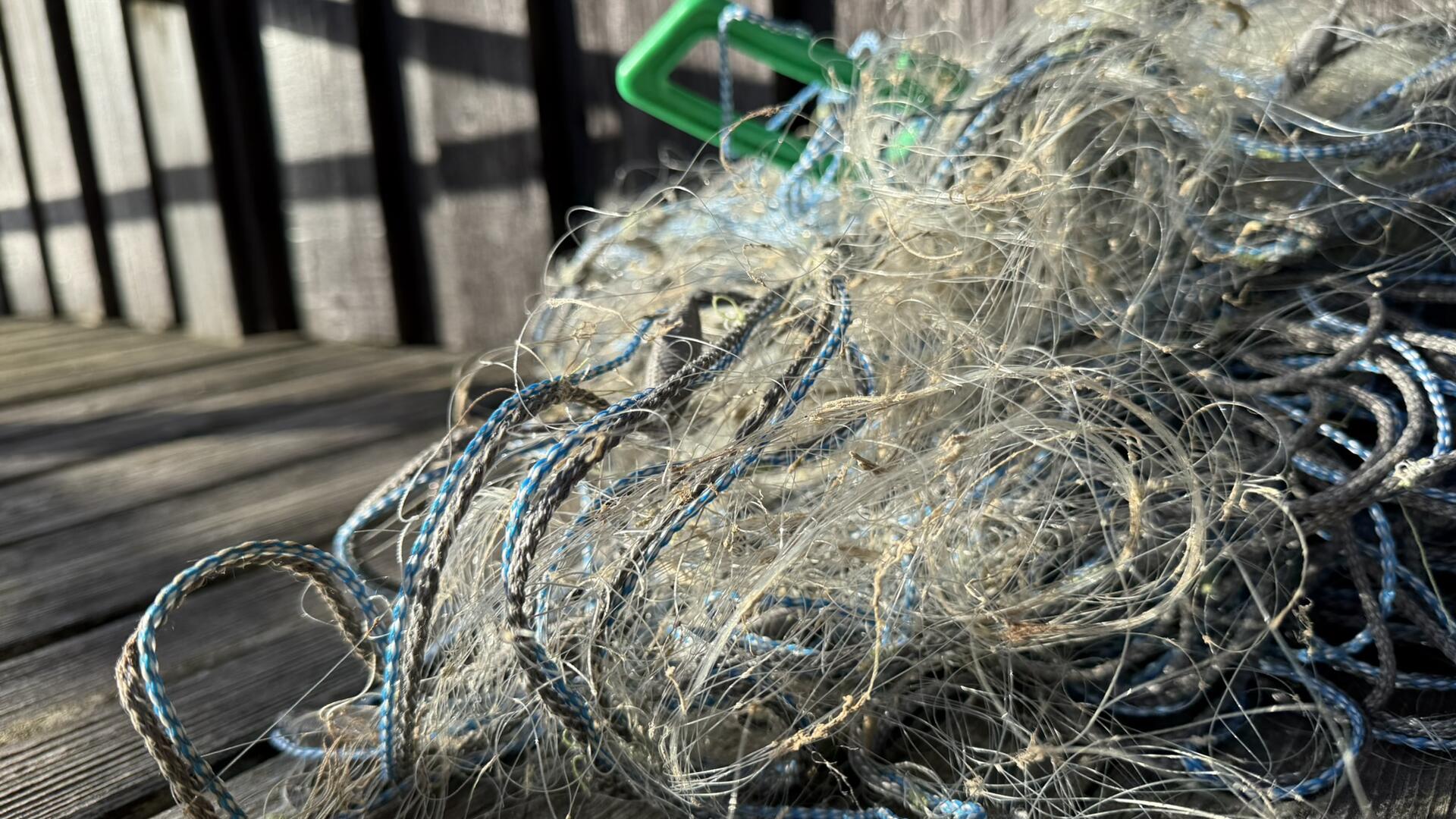 Rikkinäisiä kalaverkkoja sekaisessa kasassa laiturilla.