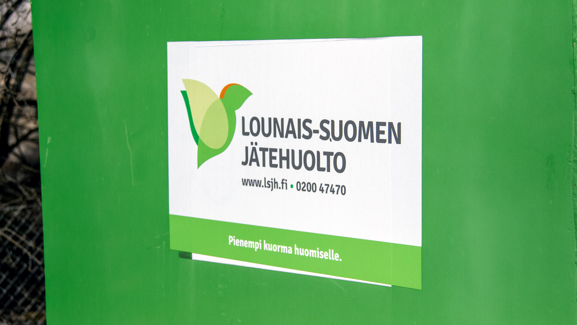 Vihreän jäteastian kyljessä on tarra, jossa lukee Lounais-Suomen Jätehuolto.