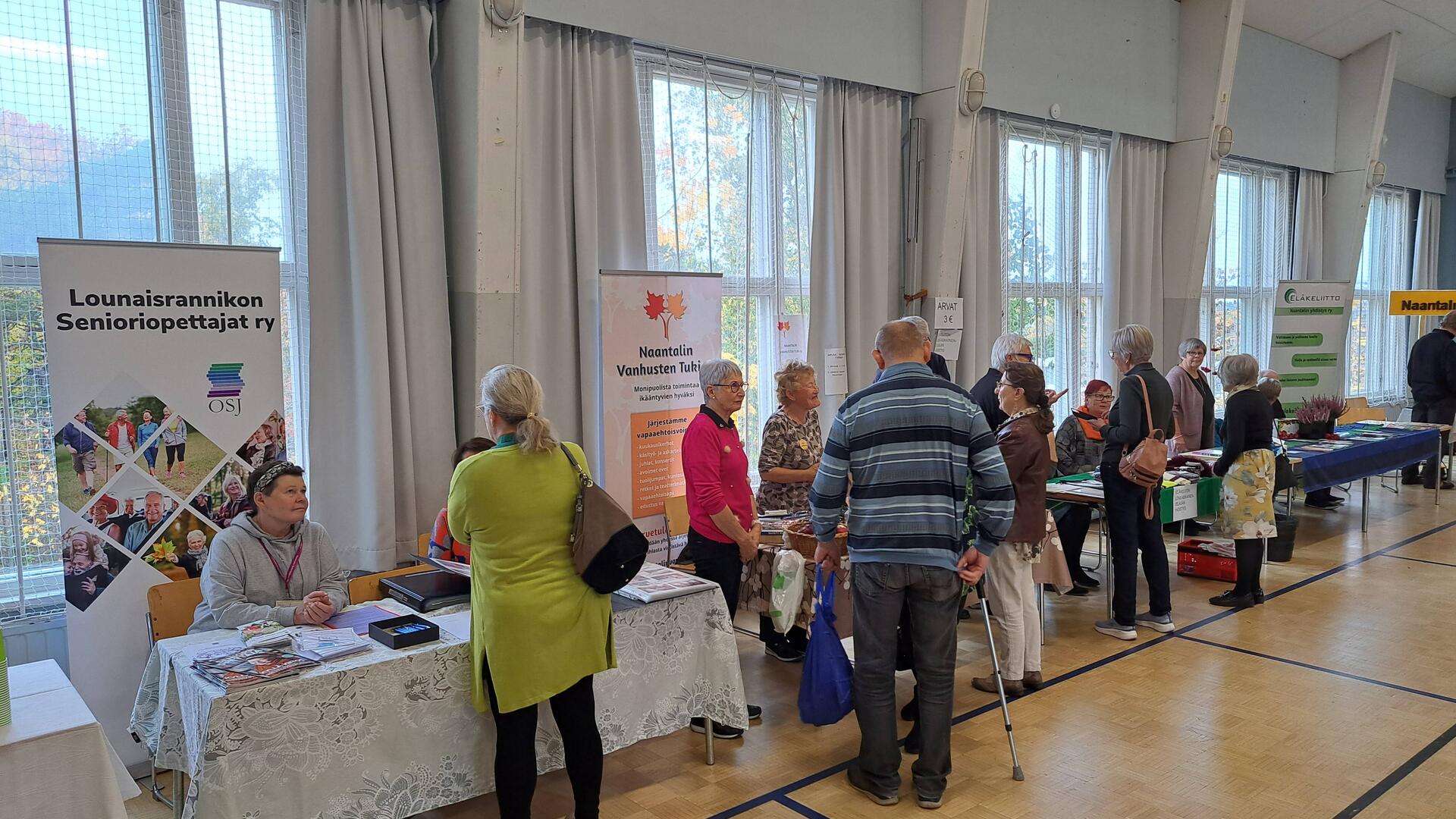 Messuvieraita esittelypöytien luona ikäihmisten messuilla