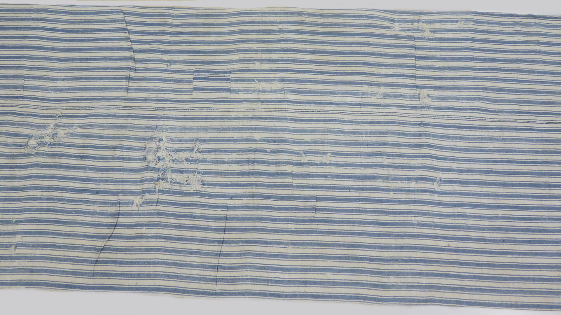 Sinivalkoraidallinen kangaspussi, paikattu ja osittain rispaantunut