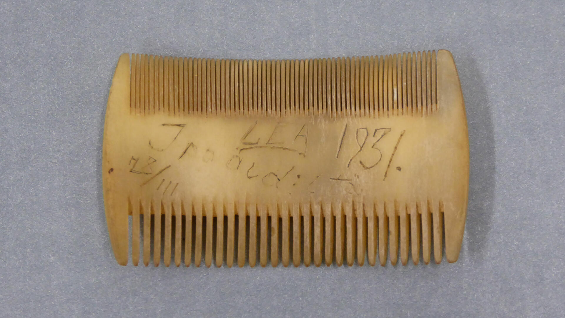 Harmaalla pohjalla kaksipuolinen kampa