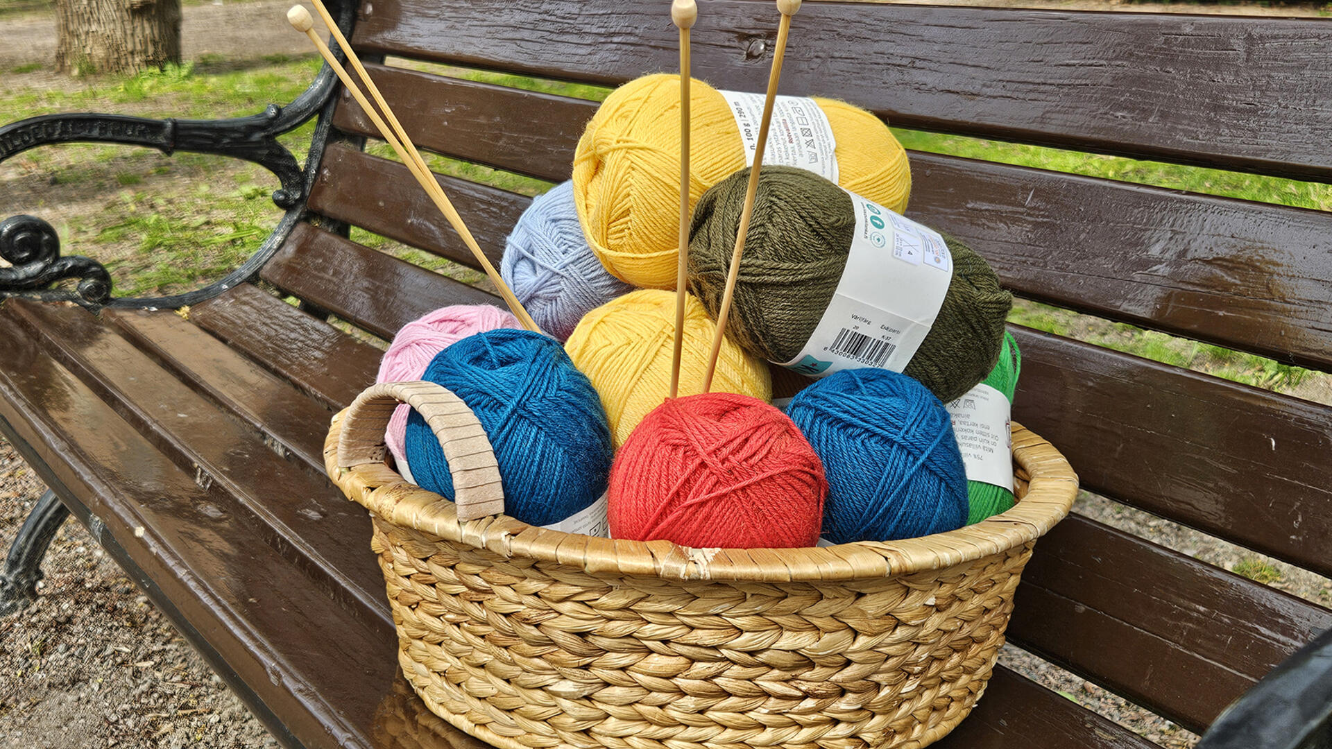 Puiston penkillä kori, jossa on värikkäitä lankoja ja puikot