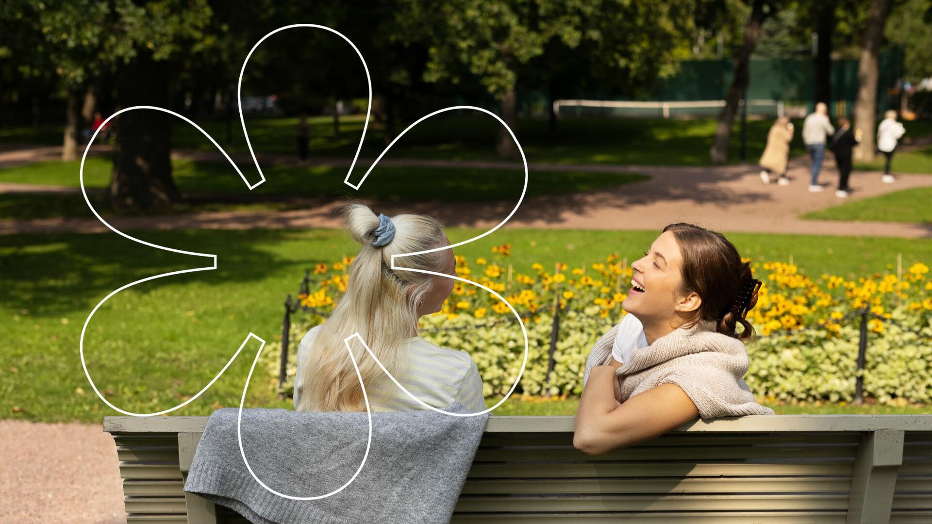 Nuoret naiset istuvat Kirkkopuiston penkillä. Kuvassa Onnellinen aurinko -elementti.