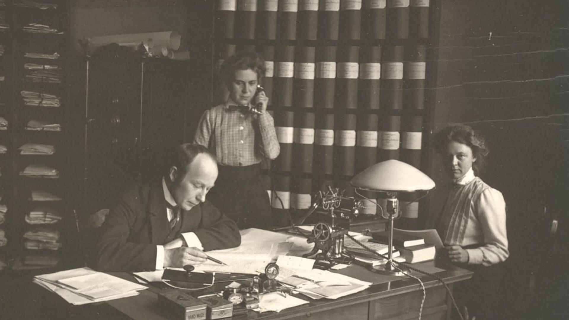 mies ja kaksi naista kirjoituspöydän takana