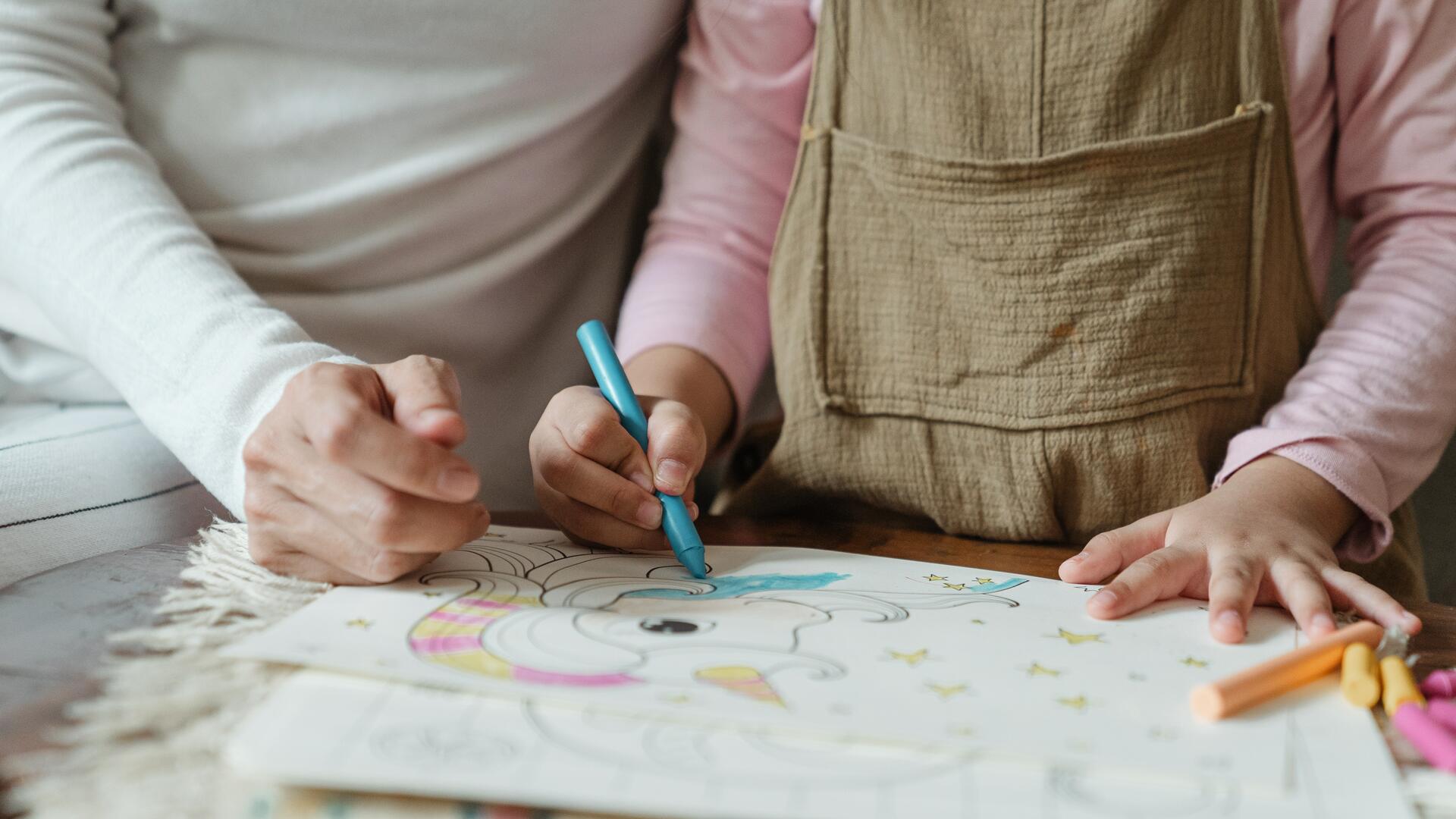 Äiti ja pieni lapsi värittävät värityskirjan kuvaa.