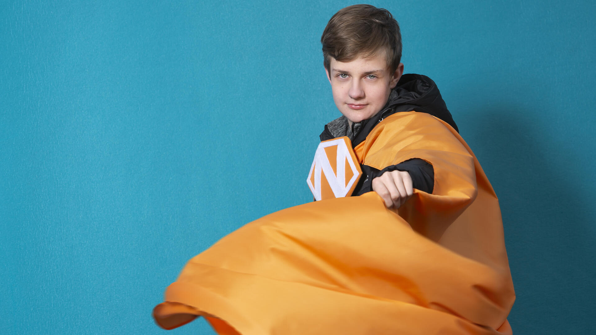 Poika oranssissa Naantali-supersankariviitassa.