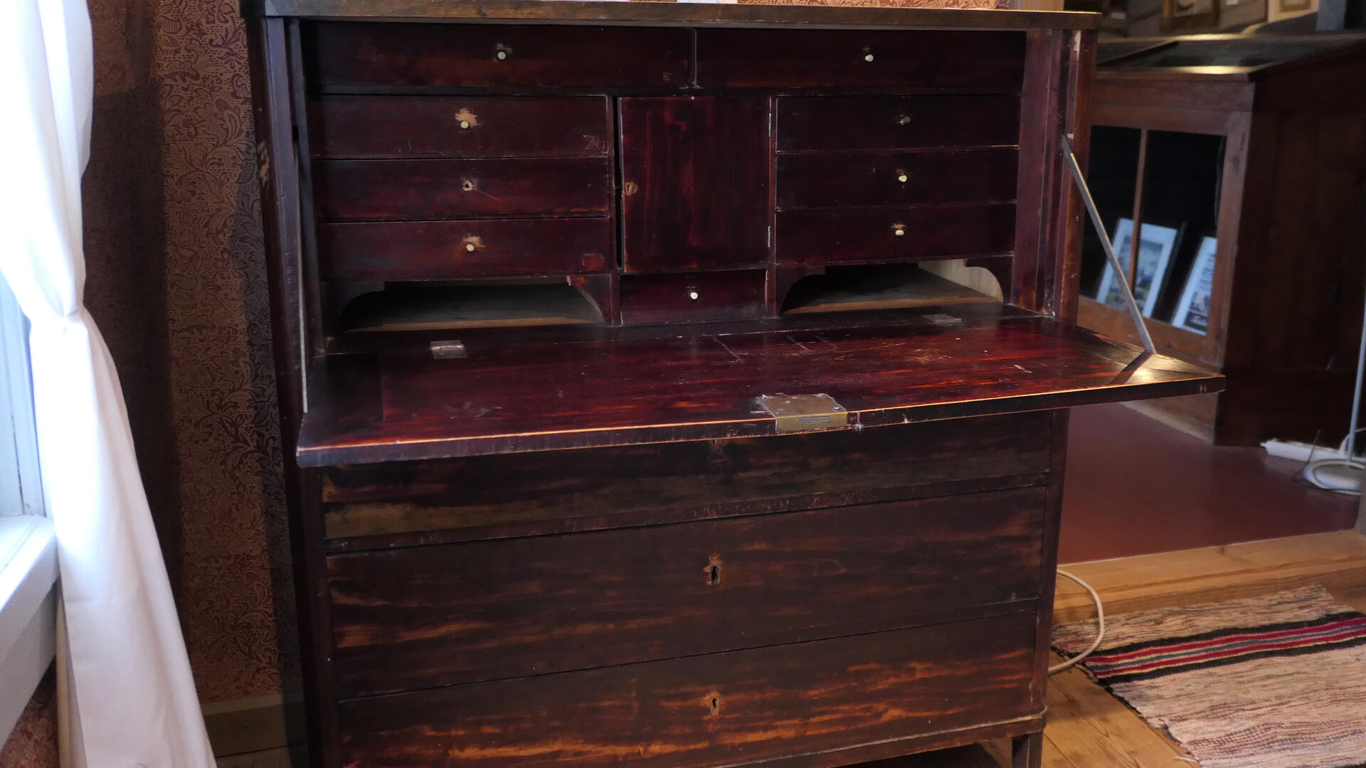 tummanruskea piironki, jonka päällä on kaksi koristekoiraa ja oikealla puulattialla näkyy räsymatto