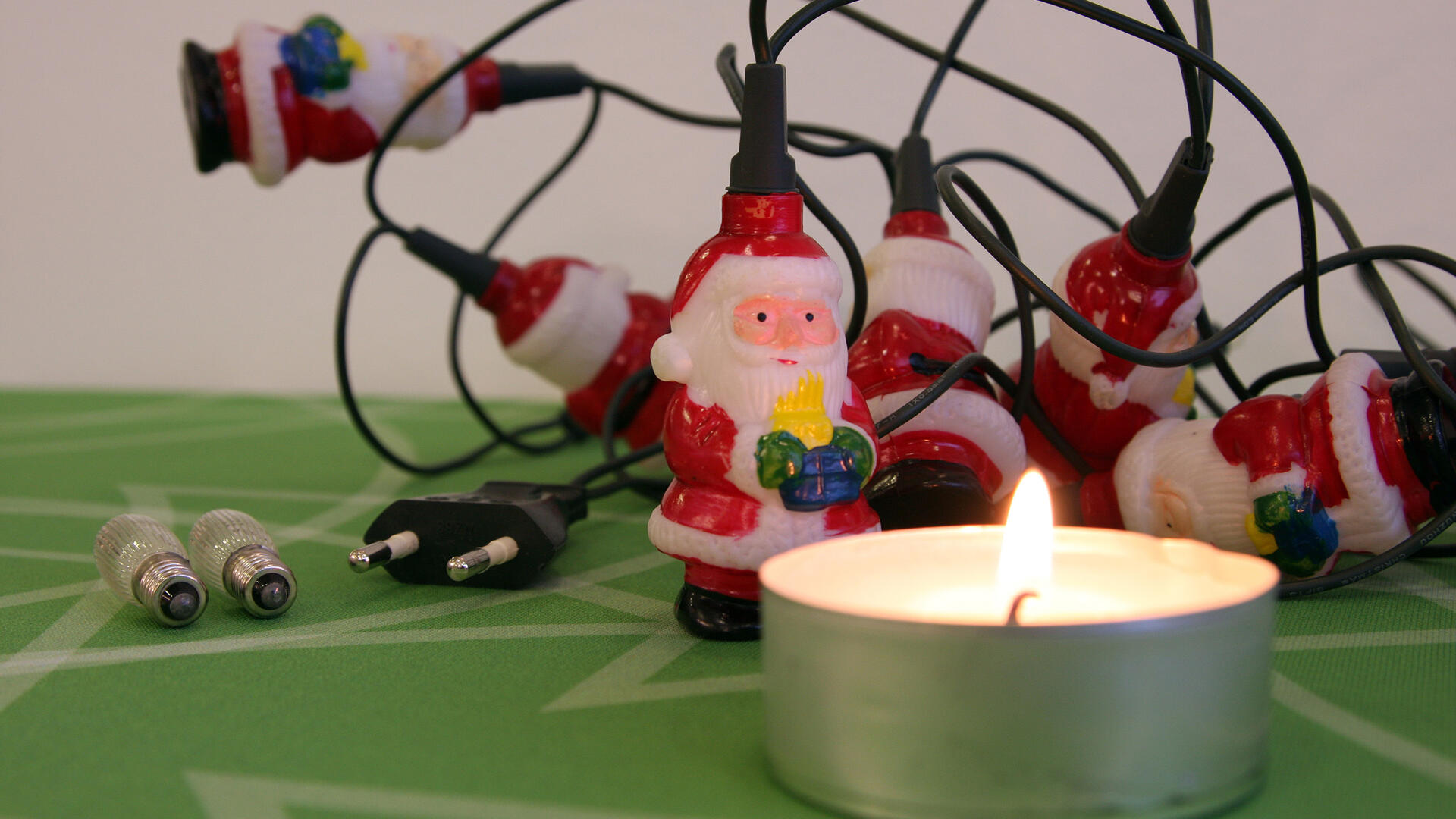 Joulupukkivalosarjan edessä palaa tuikkukynttilä.