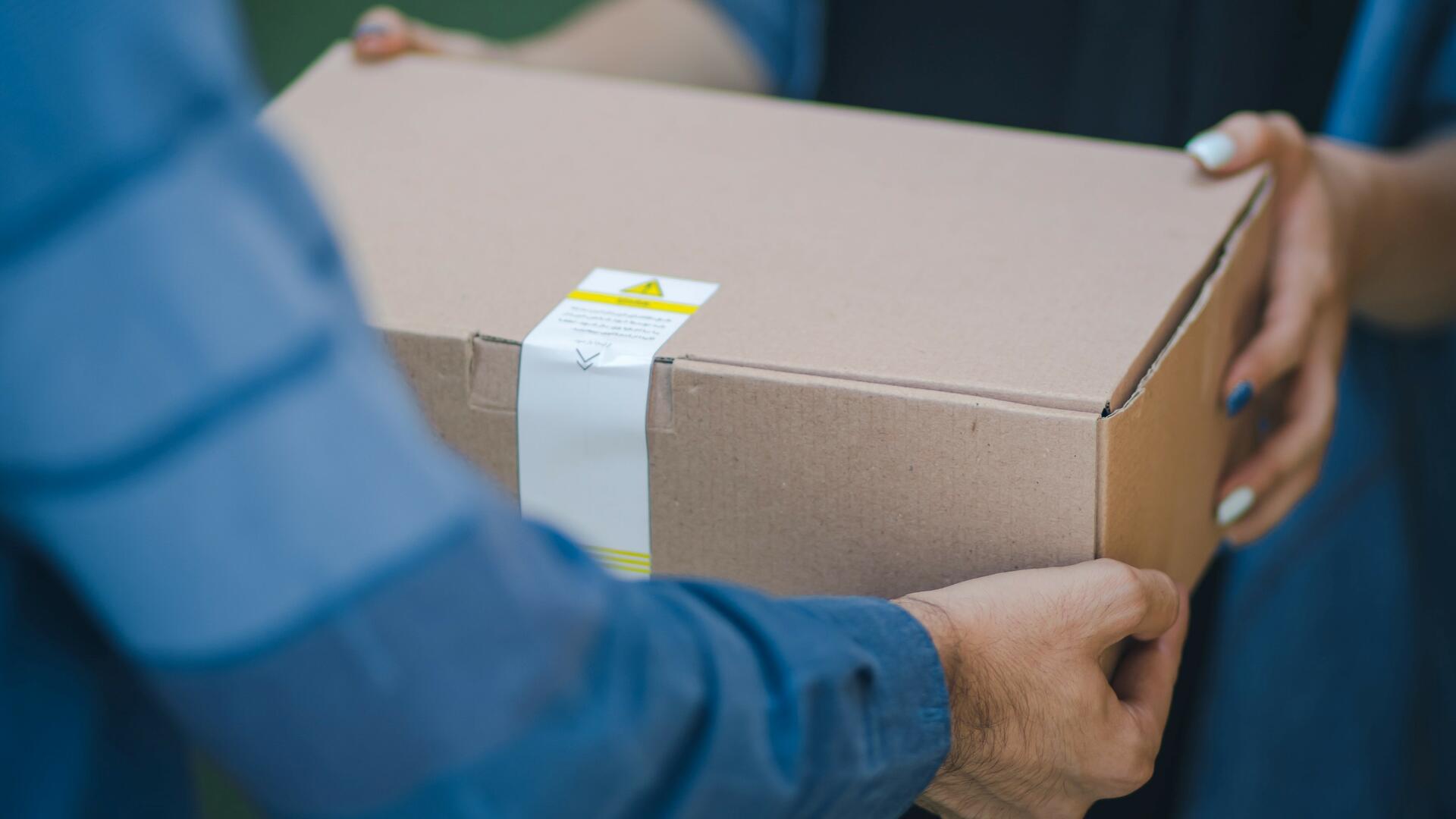 Henkilö ohjentaa toiselle postipakettia.