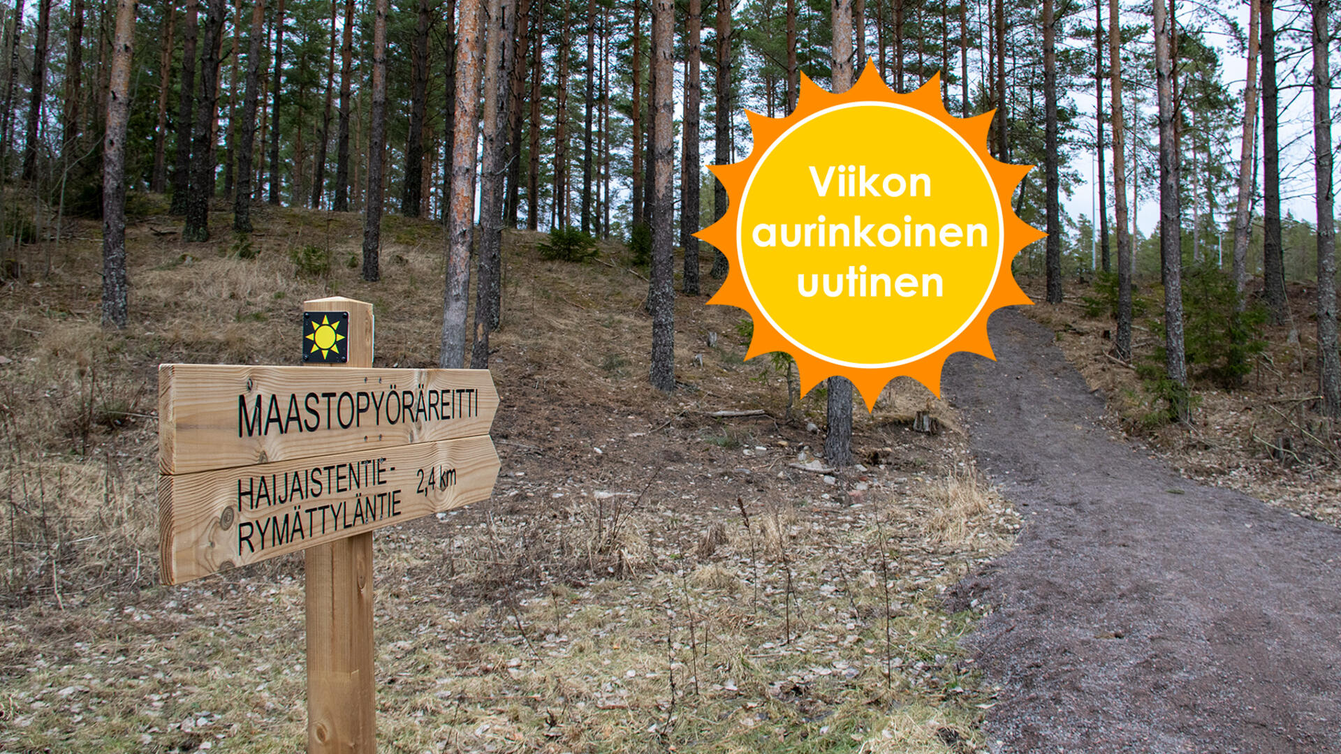 Aurinkologolla varustetussa kyltissä lukee: Maastopyöräreitti Haijaistentie-Rymättyläntie, 2,4 km. Kyltit osoittavat ylämäkeen, joka vie metsään. Viikon aurinkoinen uutinen