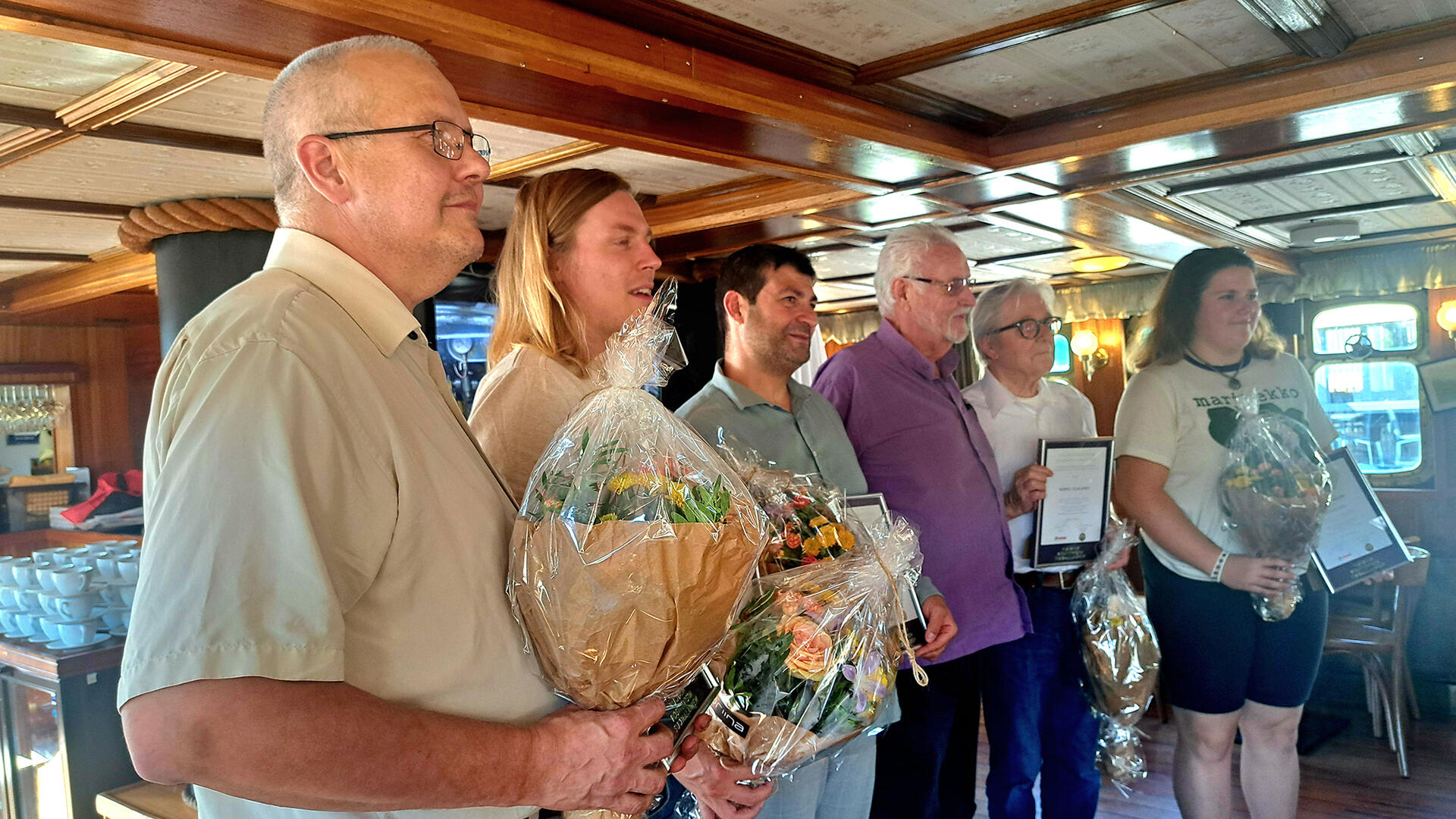 Vuoden 2024 positiivisimmiksi henkilöiksi valitut kukitettuna rivissä.