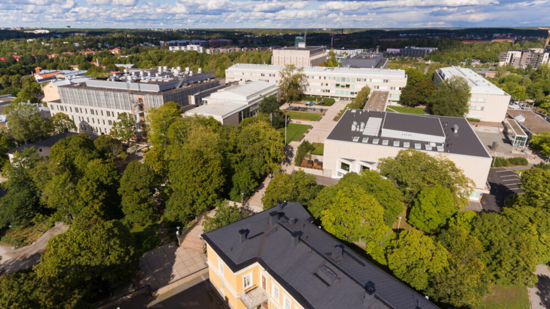 Turun yliopistonmäen rakennusten kattoja, välissä puita, taivas on pilvinen.