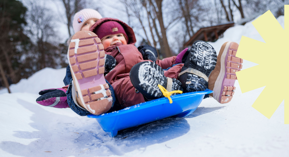 Lapset pulkkamäessä. Kuvan reunassa vaaleankeltainen graafinen aurinkoelementti.
