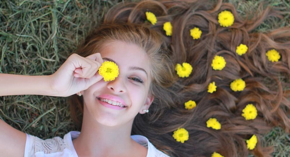 Nuori tyttö makaa nurmella kukkia hiuksissa